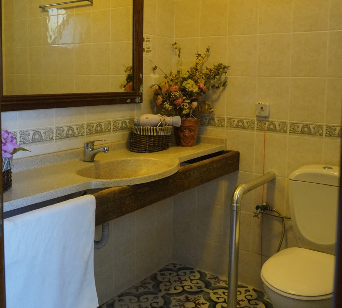 Banyo: geniş tezgâh ve lavabo, büyük ayna, tutunma barı, klozet ve duvarda acil çağrı düğmesi; tezgâhta saç kurutma makinesi.